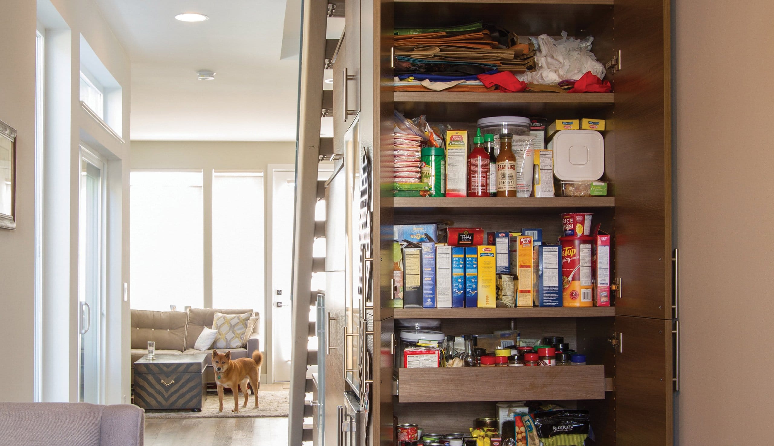 After installation of a custom kitchen pantry built in under stairway with shelving and pull out drawers in dark finish by California Closets